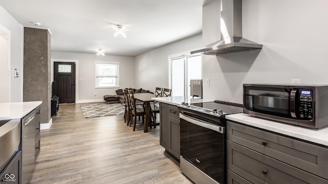 1342 N Oakland Ave, Indianapolis, IN 46201 - kitchen featuring stainless steel electric stove, wall chimney range hood, light countertops, light wood-style flooring, and baseboards
