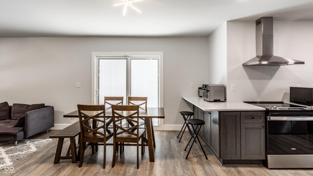1342 N Oakland Ave, Indianapolis, IN 46201 - kitchen with wall chimney exhaust hood, stainless steel range with electric cooktop, light wood finished floors, light countertops, and baseboards