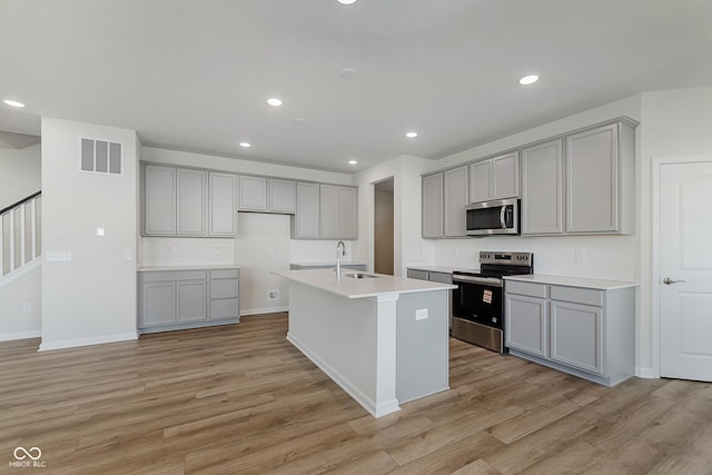 2705 Penn Ave, Plainfield, IN 46168 - kitchen with stainless steel appliances, gray cabinetry, light wood-style floors, a kitchen island with sink, and recessed lighting
