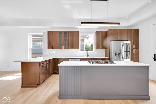 19 E Regent St, Indianapolis, IN 46225 - kitchen featuring stainless steel appliances, a sink, a peninsula, decorative backsplash, and light wood-style flooring