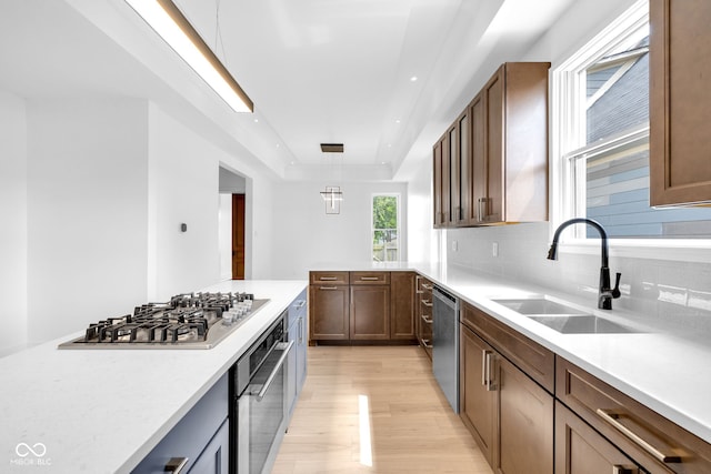 19 E Regent St, Indianapolis, IN 46225 - kitchen featuring stainless steel appliances, a sink, light wood-type flooring, tasteful backsplash, and light countertops