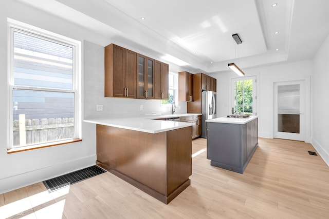 19 E Regent St, Indianapolis, IN 46225 - kitchen with a tray ceiling, light wood-style flooring, stainless steel fridge, glass insert cabinets, and light countertops
