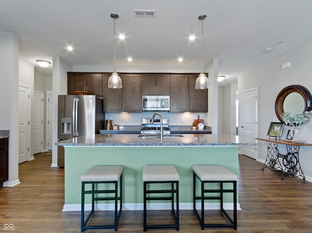 19657 Astoria Ave, Sheridan, IN 46069 - kitchen with appliances with stainless steel finishes, a sink, dark brown cabinets, dark wood-style floors, and a kitchen bar