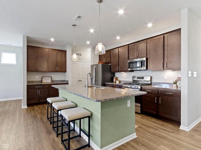 19657 Astoria Ave, Sheridan, IN 46069 - kitchen featuring stainless steel appliances, light wood finished floors, baseboards, a kitchen breakfast bar, and dark brown cabinetry
