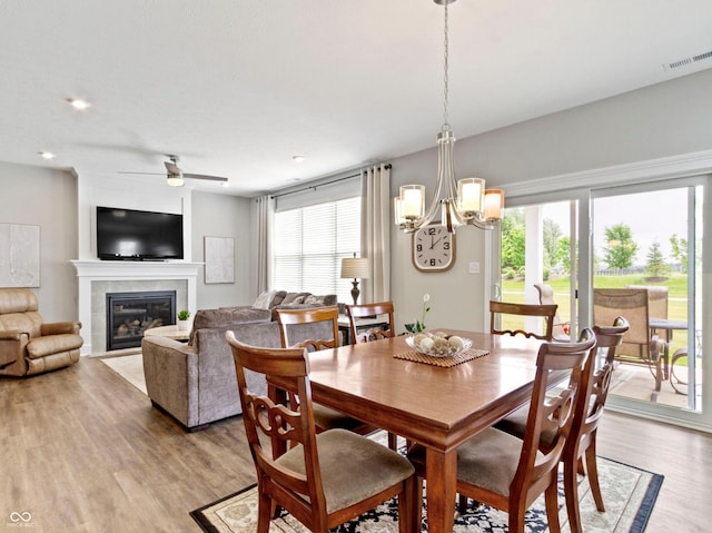 19657 Astoria Ave, Sheridan, IN 46069 - dining space with light wood-type flooring, a chandelier, a tiled fireplace, and ceiling fan