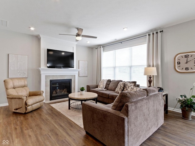 19657 Astoria Ave, Sheridan, IN 46069 - living area with wood finished floors, a ceiling fan, a tiled fireplace, baseboards, and recessed lighting