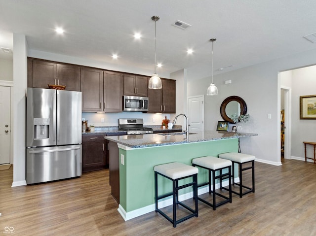 19657 Astoria Ave, Sheridan, IN 46069 - kitchen featuring appliances with stainless steel finishes, a sink, dark brown cabinetry, wood finished floors, and a breakfast bar