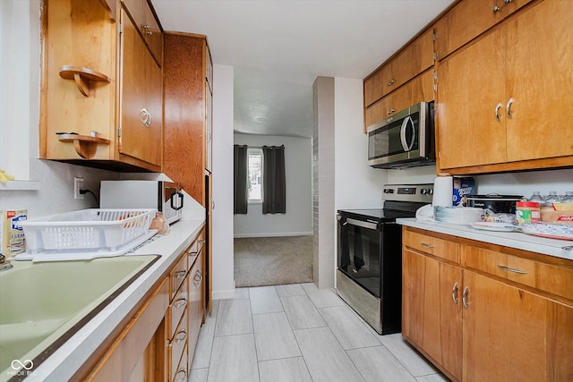 4232 Linden Ln, Anderson, IN 46011 - kitchen featuring appliances with stainless steel finishes, light countertops, brown cabinetry, and light colored carpet