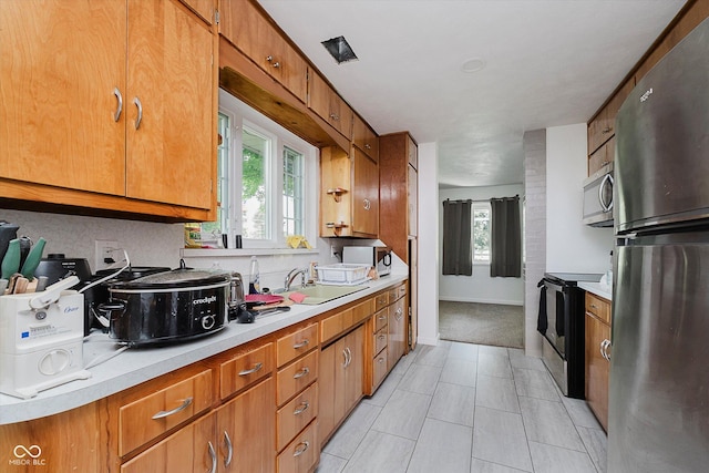 4232 Linden Ln, Anderson, IN 46011 - kitchen featuring appliances with stainless steel finishes, healthy amount of natural light, light countertops, and brown cabinets