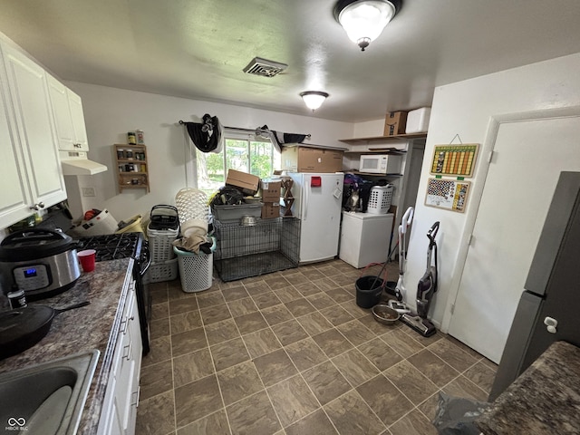 2015 Rosewood Dr, Anderson, IN 46011 - kitchen featuring white appliances, under cabinet range hood, dark countertops, a sink, and white cabinetry