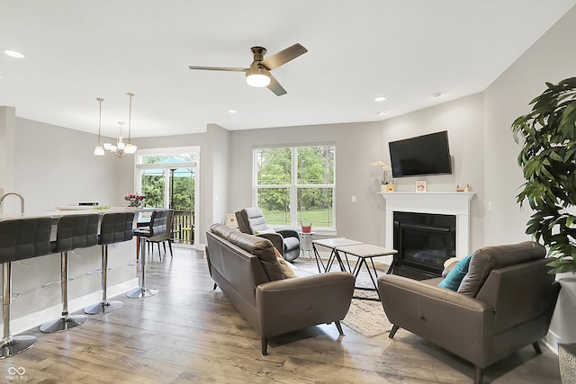 8266 Glacier Ridge Dr, Fishers, IN 46038 - living room featuring light wood finished floors, a glass covered fireplace, a ceiling fan, recessed lighting, and baseboards
