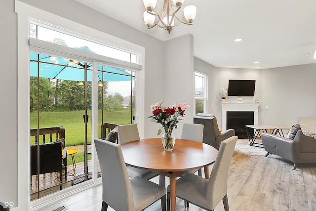 8266 Glacier Ridge Dr, Fishers, IN 46038 - dining area featuring healthy amount of natural light, a fireplace, light wood finished floors, a chandelier, and recessed lighting