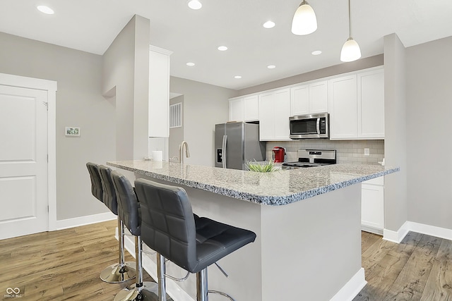 8266 Glacier Ridge Dr, Fishers, IN 46038 - kitchen with stainless steel appliances, baseboards, light wood-style flooring, light stone counters, and recessed lighting