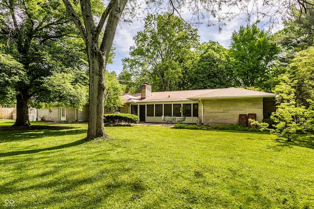 6220 Spring Mill Rd, Indianapolis, IN 46260 - back of house with a sunroom, a chimney, a lawn, and stone siding