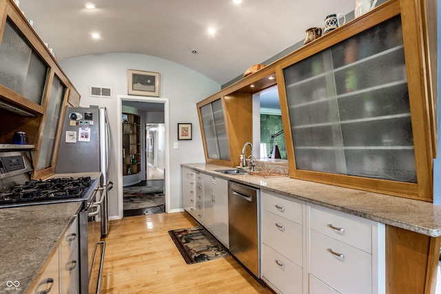 6220 Spring Mill Rd, Indianapolis, IN 46260 - kitchen featuring appliances with stainless steel finishes, a sink, light wood-style floors, vaulted ceiling, and light stone countertops