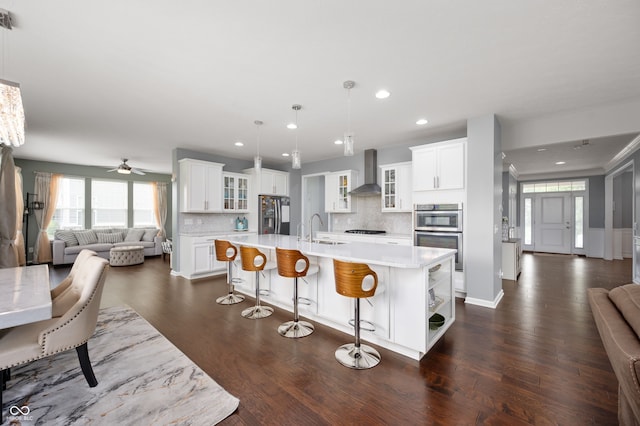 15580 Garrano Ln, Fishers, IN 46040 - kitchen featuring stainless steel appliances, wall chimney range hood, open floor plan, a sink, and light countertops