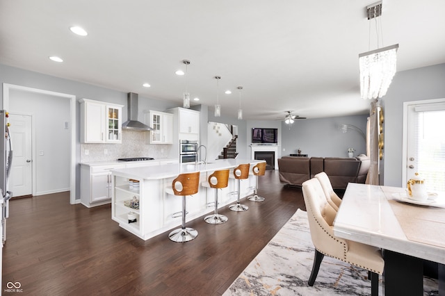 15580 Garrano Ln, Fishers, IN 46040 - kitchen with wall chimney exhaust hood, a breakfast bar, light countertops, a ceiling fan, and recessed lighting