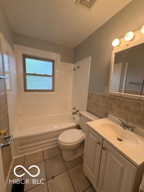 7842 Brennan Rd, Indianapolis, IN 46219 - bathroom featuring tile walls, tile patterned floors, shower / bathtub combination, toilet, and vanity