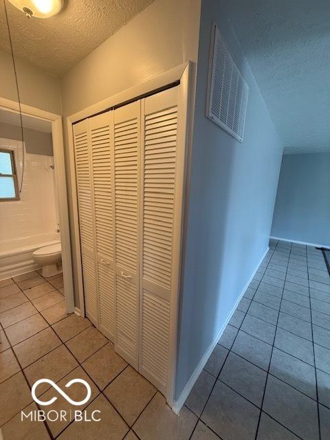 7842 Brennan Rd, Indianapolis, IN 46219 - hall with a textured ceiling and tile patterned floors