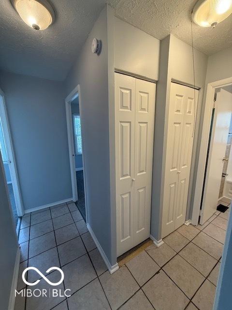 7842 Brennan Rd, Indianapolis, IN 46219 - corridor featuring a textured ceiling, light tile patterned floors, and baseboards