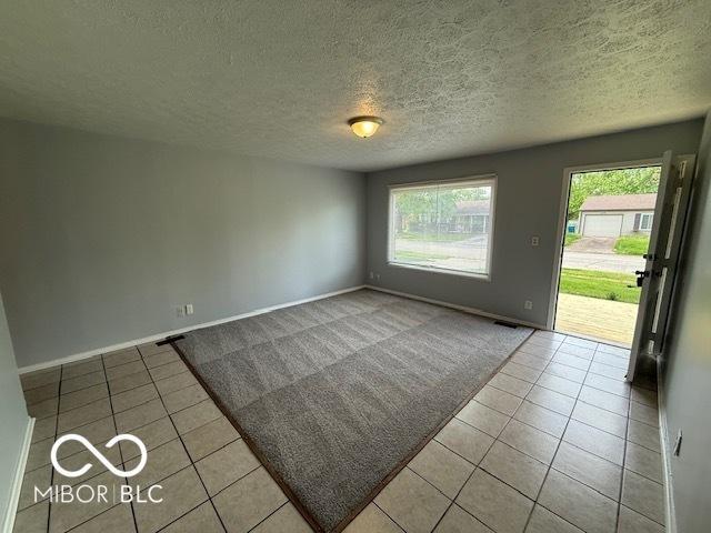 7842 Brennan Rd, Indianapolis, IN 46219 - spare room featuring tile patterned floors, baseboards, a textured ceiling, and carpet flooring