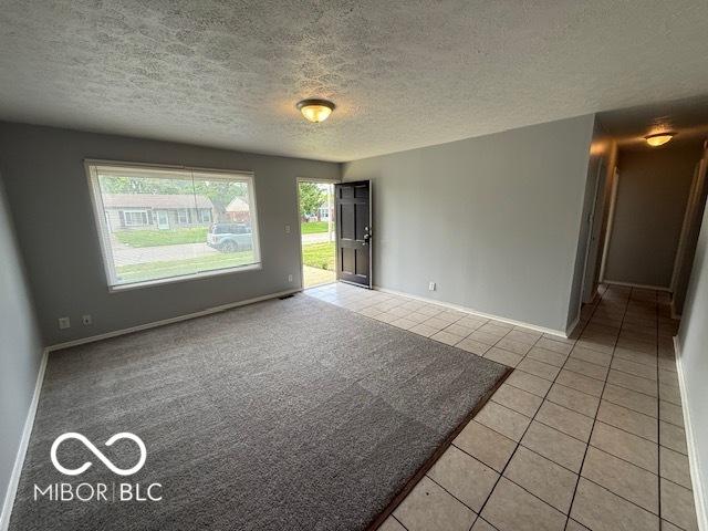 7842 Brennan Rd, Indianapolis, IN 46219 - spare room with light tile patterned flooring, a textured ceiling, and baseboards