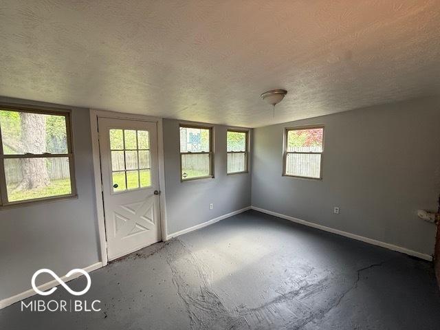 7842 Brennan Rd, Indianapolis, IN 46219 - spare room with a textured ceiling, baseboards, and concrete floors