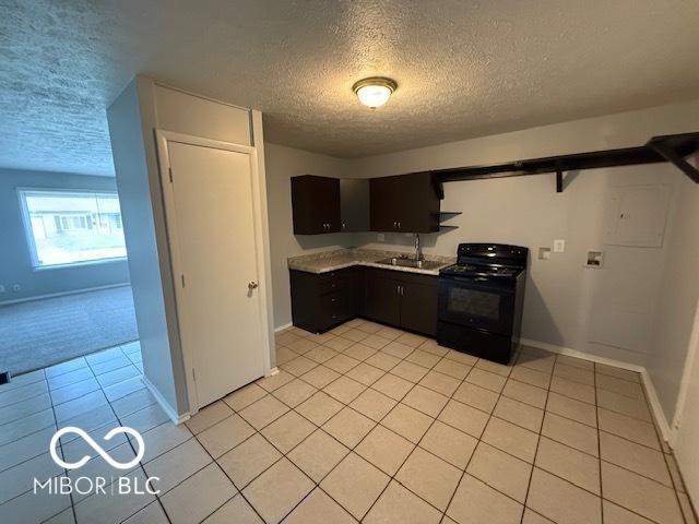 7842 Brennan Rd, Indianapolis, IN 46219 - kitchen with electric range, a textured ceiling, light tile patterned floors, a sink, and baseboards