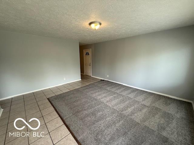 7842 Brennan Rd, Indianapolis, IN 46219 - tiled empty room with baseboards and a textured ceiling
