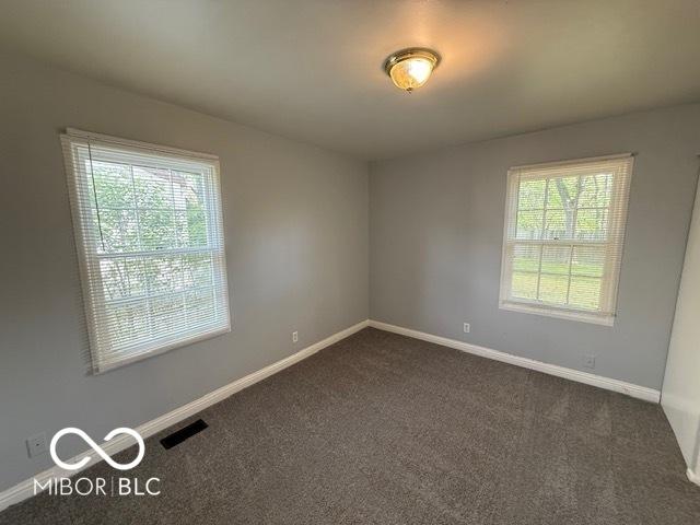 7842 Brennan Rd, Indianapolis, IN 46219 - spare room featuring dark colored carpet and baseboards
