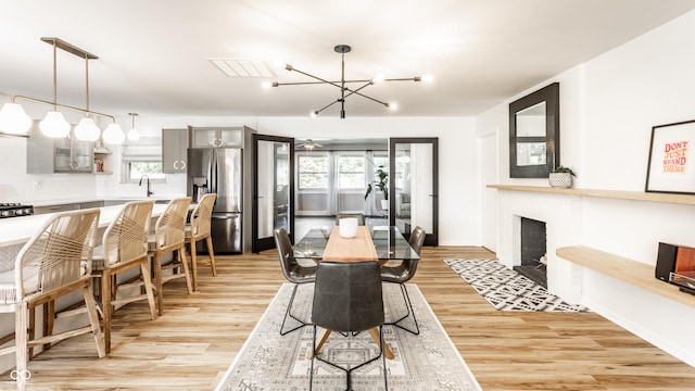 7110 N Layman Ave, Indianapolis, IN 46250 - dining area featuring a chandelier, light wood-style floors, baseboards, and a tile fireplace