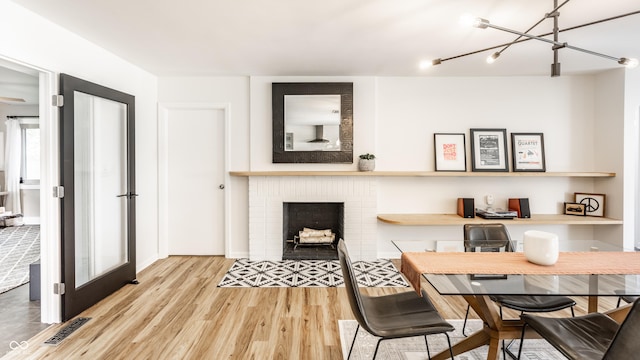 7110 N Layman Ave, Indianapolis, IN 46250 - dining space with wood finished floors, a chandelier, and a brick fireplace