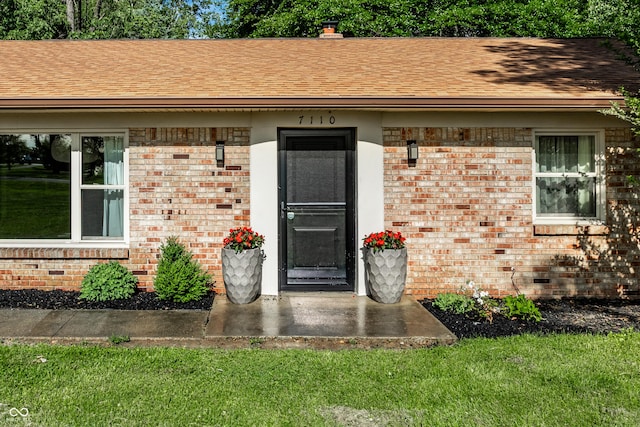 7110 N Layman Ave, Indianapolis, IN 46250 - doorway to property with brick siding, roof with shingles, and a yard
