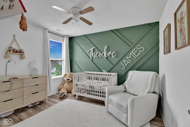 2829 Beachwalk Ln, Kokomo, IN 46902 - bedroom with a nursery area, a textured ceiling, wood finished floors, and a ceiling fan