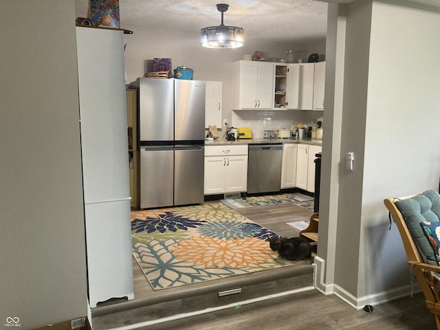 1114 N Olney St, Indianapolis, IN 46201 - kitchen with stainless steel appliances, wood finished floors, white cabinetry, tasteful backsplash, and a textured ceiling