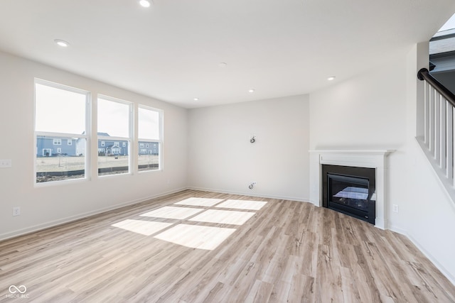 18967 Seaforth Way, Westfield, IN 46074 - unfurnished living room with light wood-style flooring, a glass covered fireplace, recessed lighting, and baseboards