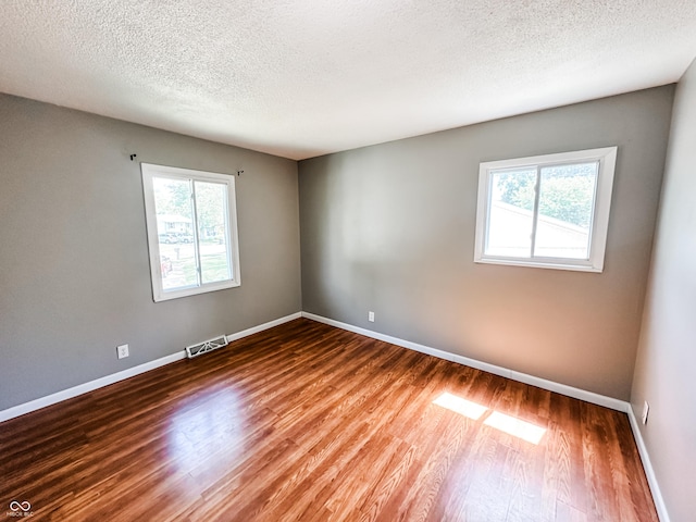 2419 Tamarack Pl, Anderson, IN 46011 - empty room with healthy amount of natural light, baseboards, wood finished floors, and a textured ceiling