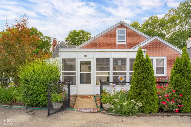 2021 Chestnut St, Columbus, IN 47201 - view of front facade with a sunroom, a chimney, and brick siding