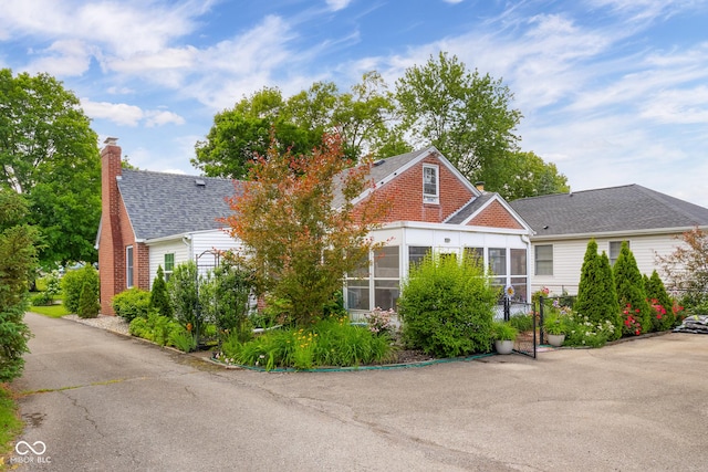 2021 Chestnut St, Columbus, IN 47201 - view of front of property featuring a sunroom, a chimney, and a shingled roof
