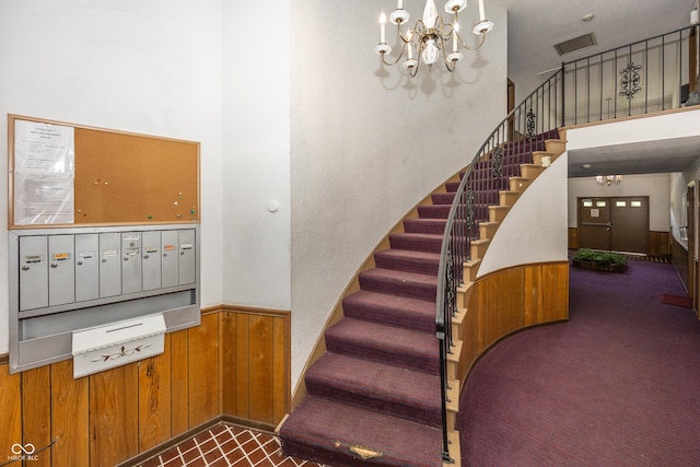 1602 Queensbridge Sq Unit 7, Indianapolis, IN 46219 - staircase featuring a towering ceiling, wood walls, carpet floors, wainscoting, and a chandelier