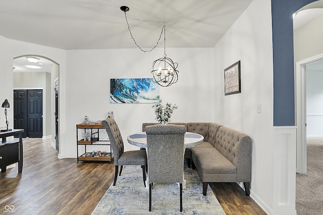 dining space featuring arched walkways, wood finished floors, and a chandelier