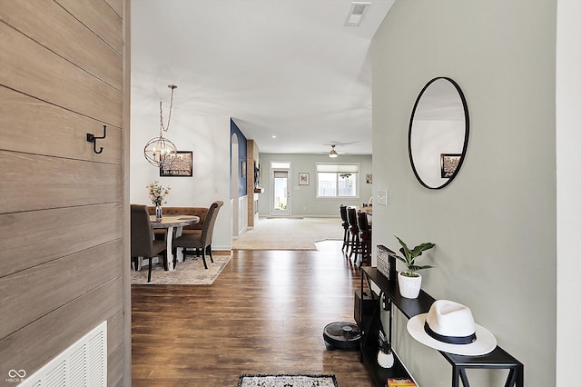 hall with a chandelier, dark wood-style flooring, and baseboards