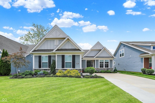 craftsman-style home with board and batten siding, a front lawn, stone siding, and concrete driveway