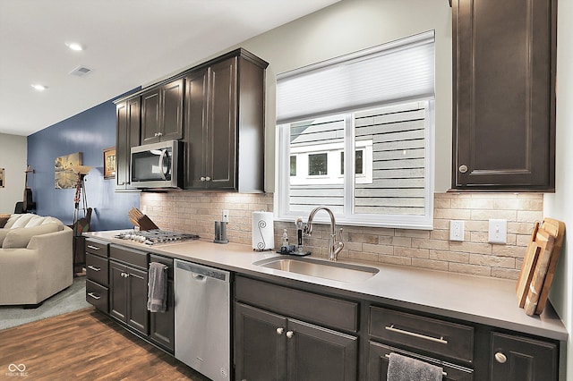 kitchen featuring a sink, stainless steel appliances, dark wood-style floors, tasteful backsplash, and open floor plan