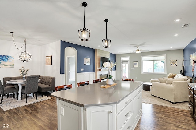 kitchen with open floor plan, a kitchen island, a ceiling fan, arched walkways, and recessed lighting