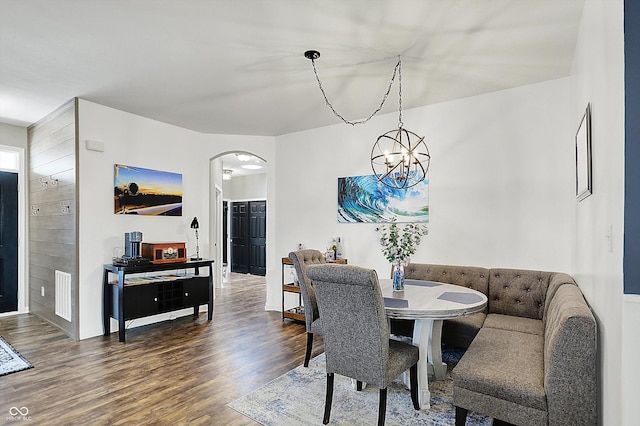 dining room with arched walkways, wood finished floors, and a chandelier