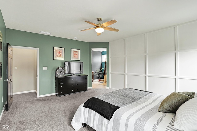 bedroom featuring carpet floors, baseboards, a decorative wall, and ceiling fan
