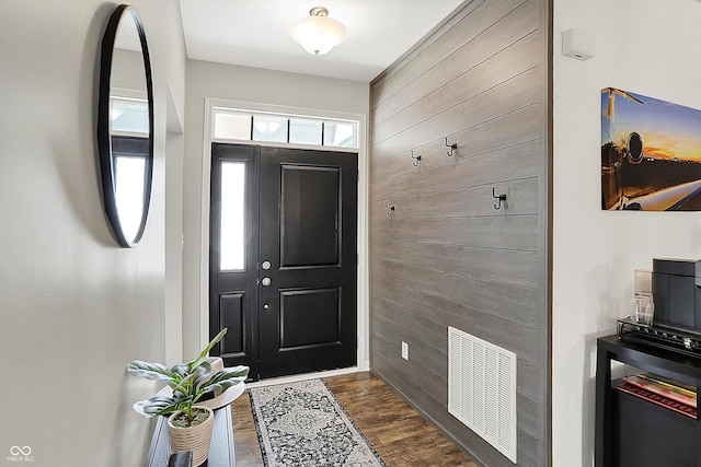 foyer entrance featuring dark wood-style floors and wooden walls