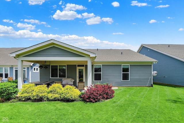 back of property featuring a lawn and roof with shingles