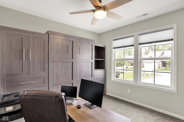 carpeted office space with a ceiling fan and baseboards